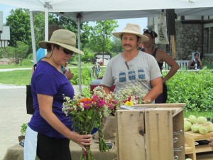 Kyle from Harvest Moon Farm showing fresh cut flowers to a visitor at Duke Farms' Farm To Table farmers market.